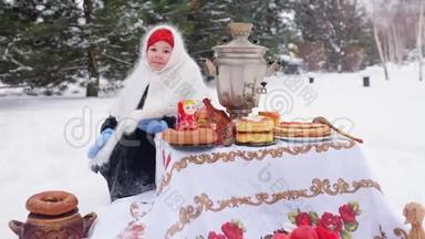 一个穿着裘皮大衣、戴着俄罗斯风格围巾的小女孩坐在节日的餐桌旁，扮演着一个俄罗斯的马崔什卡